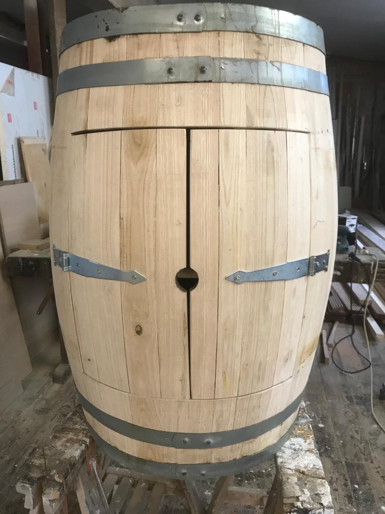 Ein großes hellbraunes Holzfass mit Metallringen und ungewöhnlichem Schlitz in der Mitte